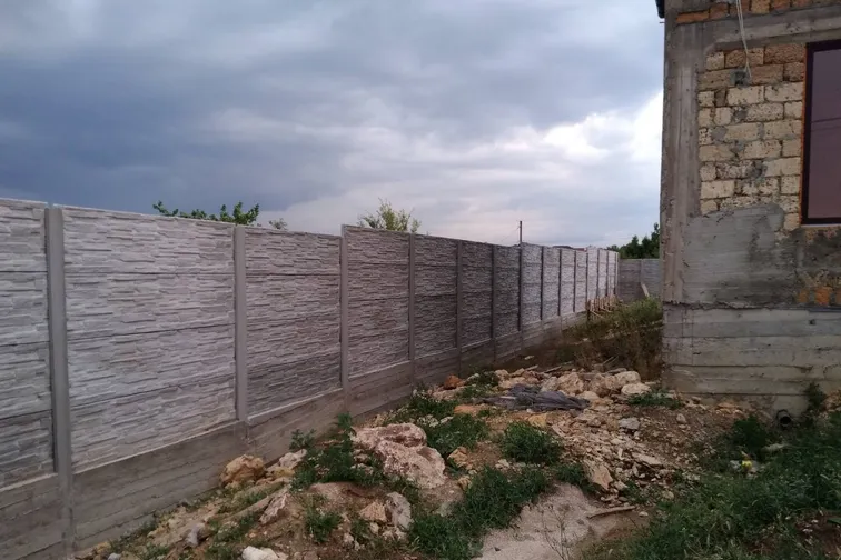 Еврозабор рядом с домом, облицованным природным камнем